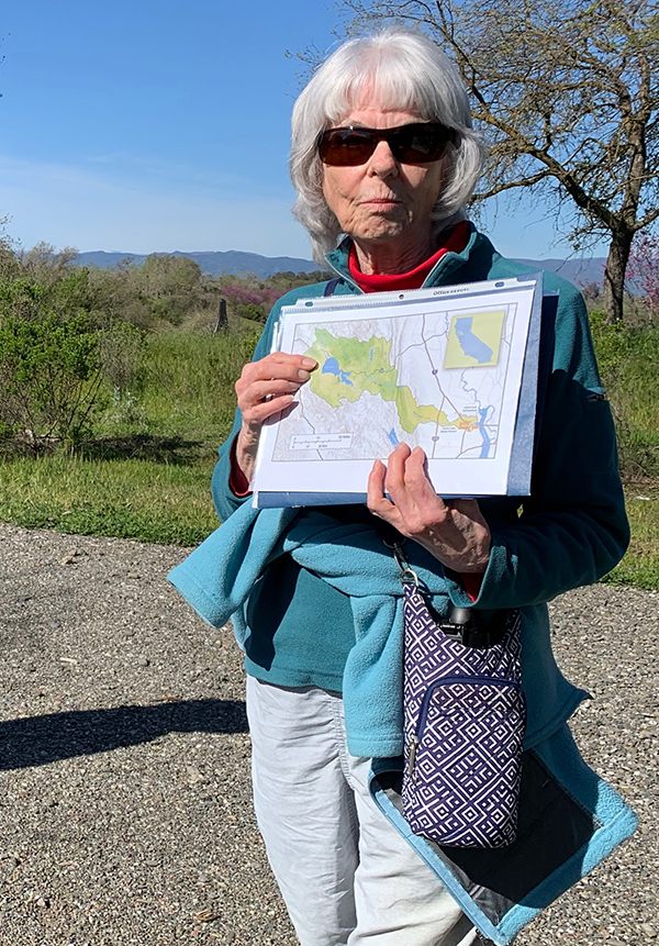Silver-haired Elize with sunglasses holding a map of the Cache Creek Watershed