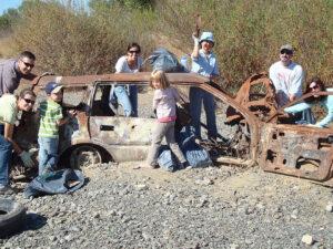Group of volunteers around a rusty car frame
