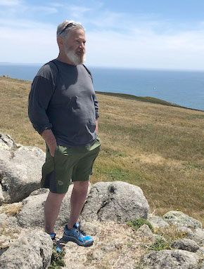 Jim Herrington standing on rocks against a prarie background