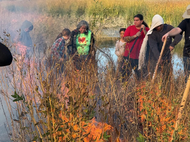 Diana Almendariz teaching a group of students and children next to flames at Leok Po 2032