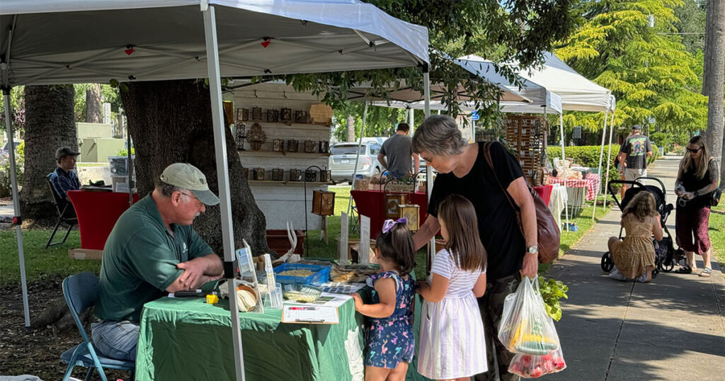 Woman and two girls at the Conservancy's booth - Woodland Farmers Market