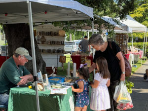 Woman and two girls at the Conservancy's booth - Woodland Farmers Market