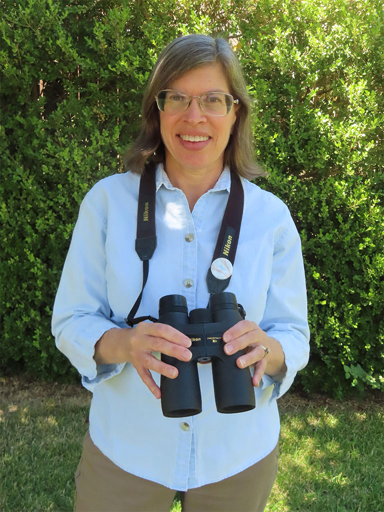 Young woman in blue shirt holding binoculars