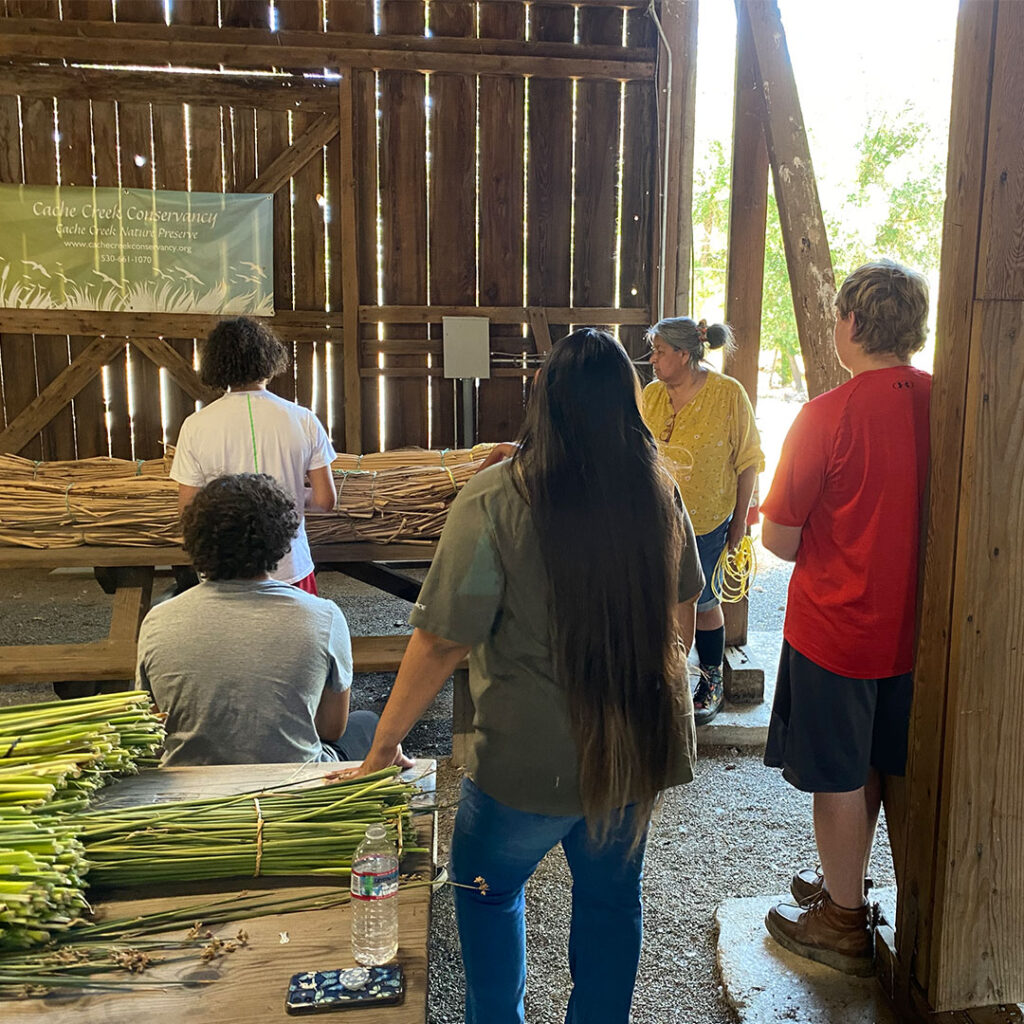 Diana Almendariz surrounded by students in the old barn at Cache Creek Nature Preserve