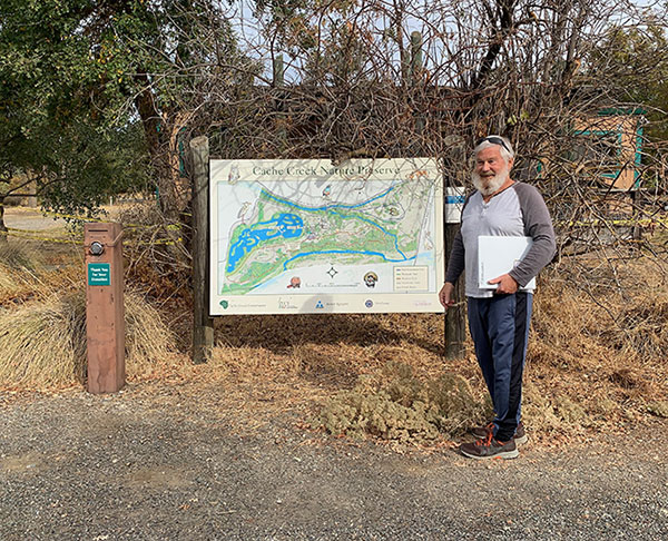 Jovial man with white beard standing next to map kiosk of Cache Creek Nature Preserve